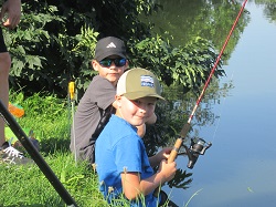 Kinder sitzen beim Teich